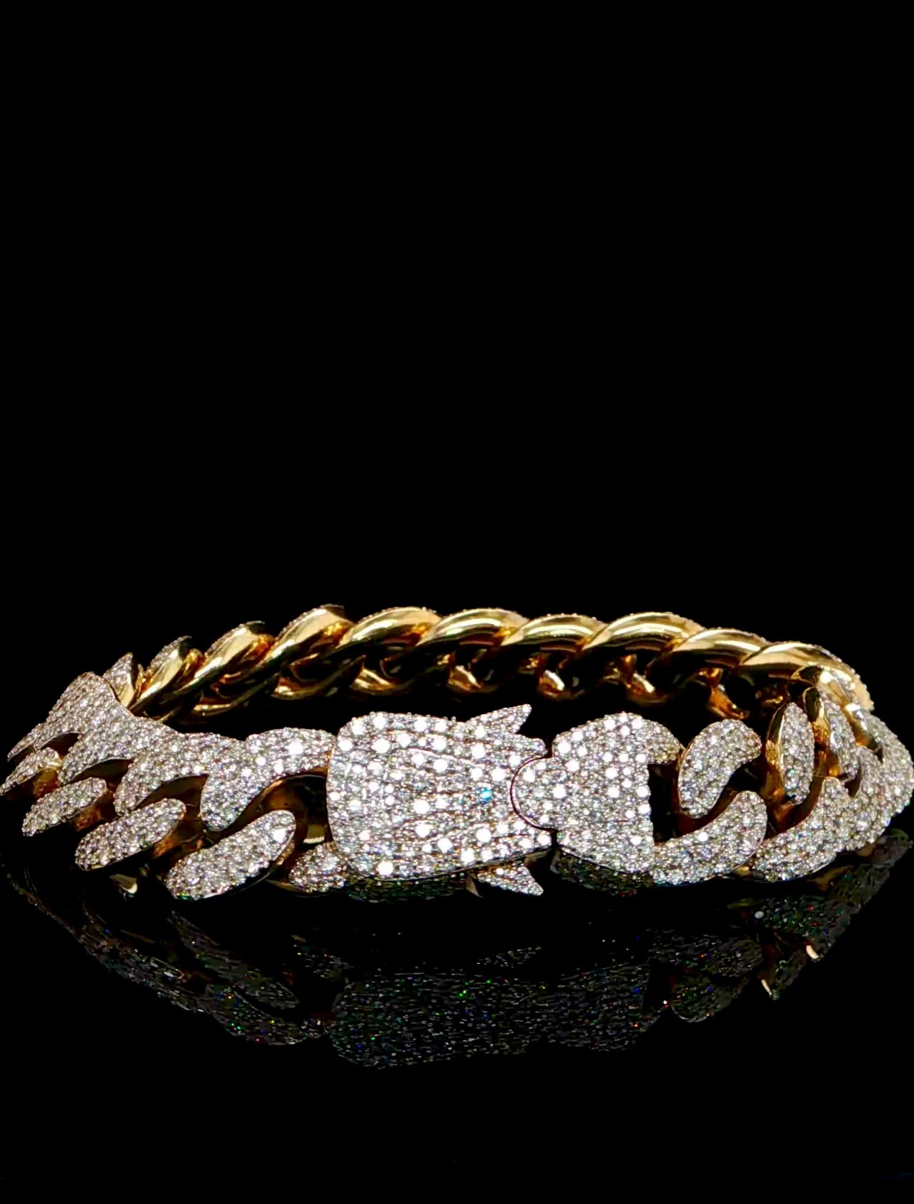 Gold chain bracelet with diamond accents on a black background